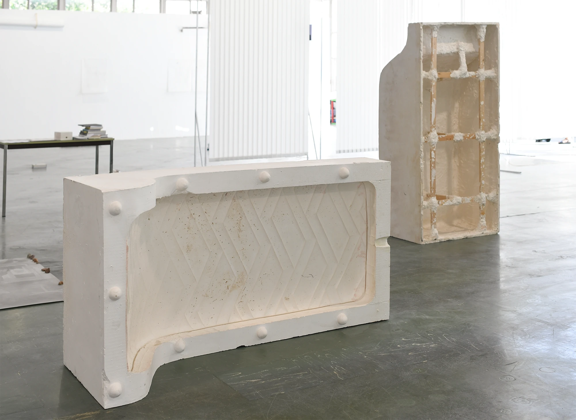 Aniruddha Biswas, La courbe, 2022, exhibition view showing a plaster mattress mould installed in a large exhibition space with other works in the background.